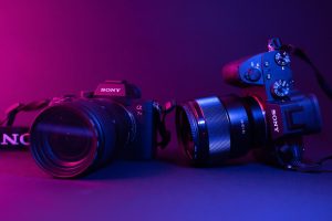 Photographie packshot de deux appareils photo Sony sur un fond dégradé bleu et rose